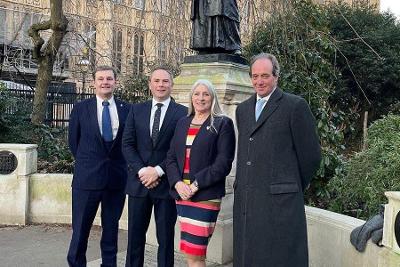 Four members of the Business Board standing in front of a statue outside the House of Lords